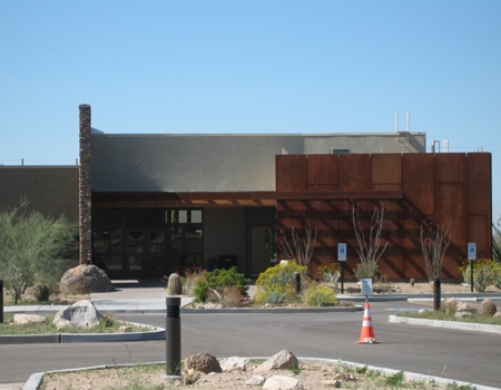 Exterior view of Usery Mountain Regional Parks modern desert nature center building with rust-colored metal panels, desert landscaping, and a clear blue sky.