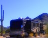An RV camper with a Saguaro on the left side and mountains behind the RV at Cave Creek Regional Park. 